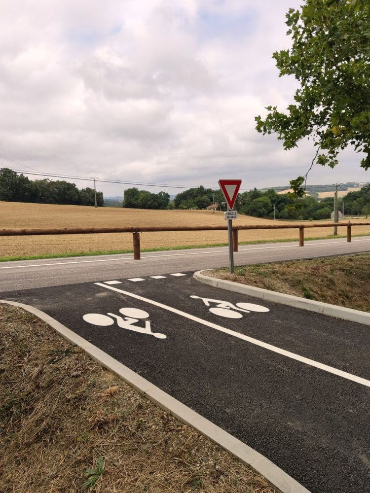 Un aménagement le long de la piste cyclable pour accéder au parking de Lahitte, avec lisse en bois pour séparer la route destinée aux automobilistes